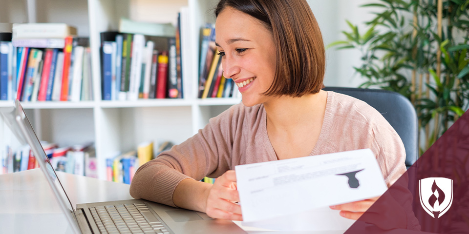 female holding a resume and looking at her laptop