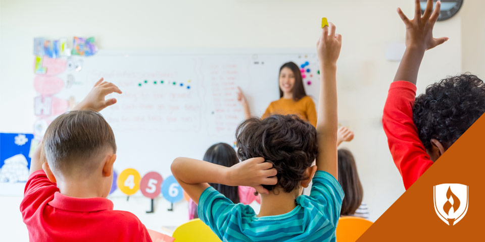 young boys raising their hands for teacher in front of classroom