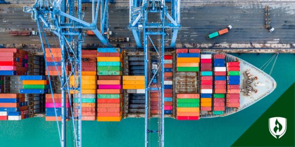 A ship full of colorful cargo boxes waits at a loading dock