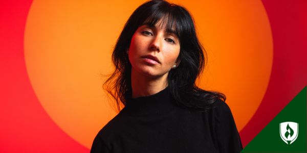 A woman looks at the camera with orange and red circles in the background