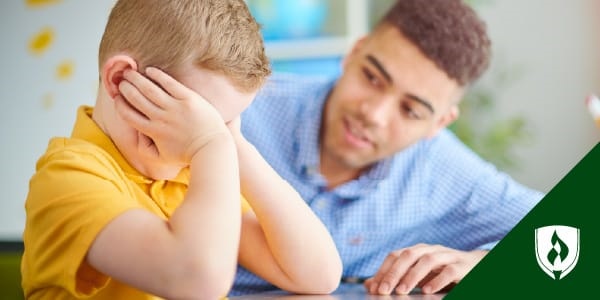 photo of an ece teacher and a student talking while the student's head is in his hands representing what is trauma informed education