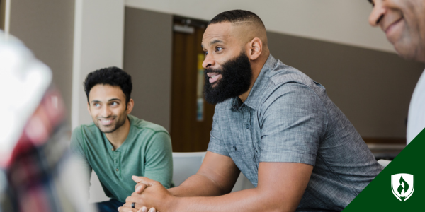 men sitting in circle leaning forward engaged in conversation