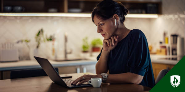 A Woman with ear pods works through an RN to BSN online course at her kitchen table at night