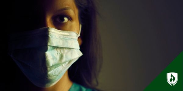 A nurse in a face mask looks closely at the camera