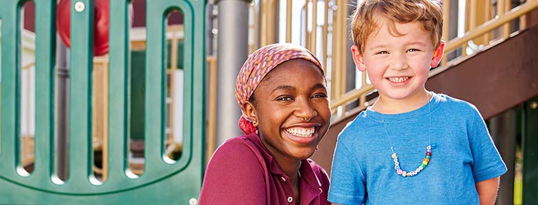 Teacher and young boy smiling in playground