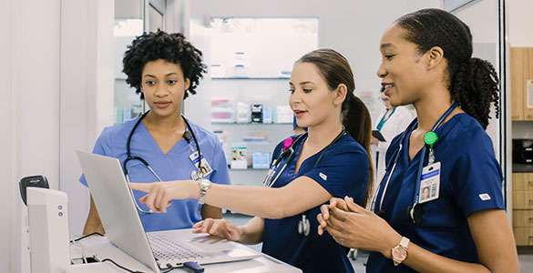 nurses talking around a laptop