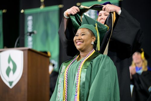 Happy Rasmussen University graduate during commencement ceremony hooding